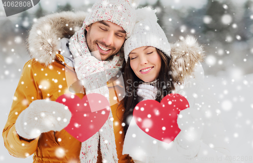 Image of happy couple with red hearts over winter landscape