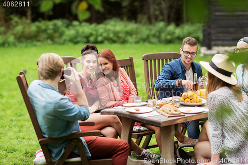 Image of happy friends having dinner at summer garden party