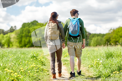 Image of happy couple with backpacks hiking outdoors