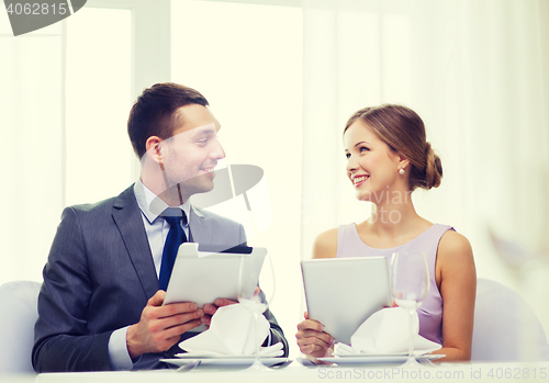 Image of couple with menus on tablet pc at restaurant