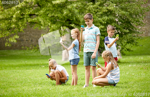 Image of kids with smartphones playing game in summer park
