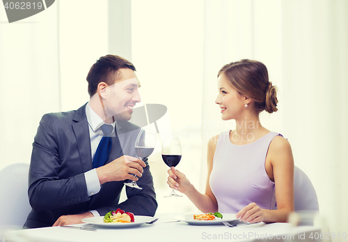 Image of couple with main course and red wine at restaurant