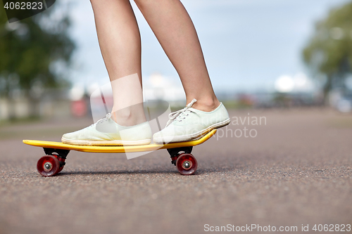 Image of close up of female feet riding short skateboard