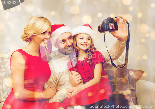Image of smiling family in santa helper hats taking picture