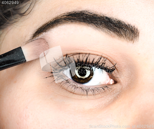 Image of Female lying final touch of makeup at extreme closeup