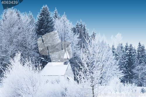 Image of Snow-capped little wooden chapel in frosty winter forest