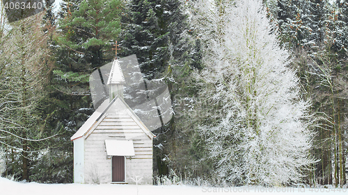 Image of Winter view little snow-capped rural wooden church in frozen for