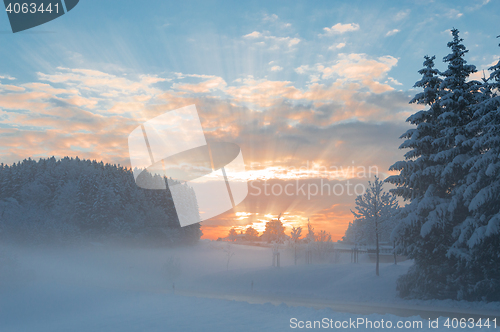 Image of Winter morning snowy scenery with dawn sunlight rays breaking cl