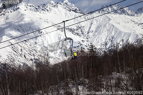 Image of Skiers on ski-lift in snow mountains at winter sun day