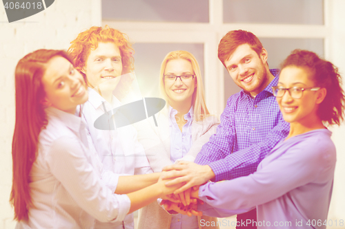 Image of team with hands on top of each other in office