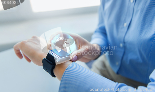 Image of close up of hands and globe hologram on smartwatch