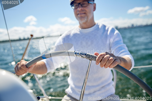 Image of senior man at helm on boat or yacht sailing in sea