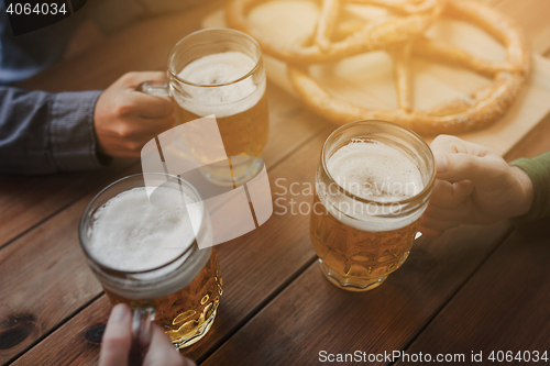Image of close up of hands with beer mugs at bar or pub