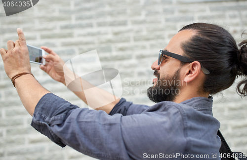 Image of hipster man taking picture on smartphone