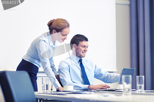 Image of businessman and secretary with laptop in office