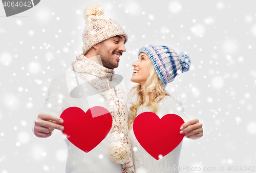 Image of smiling couple in winter clothes with red hearts