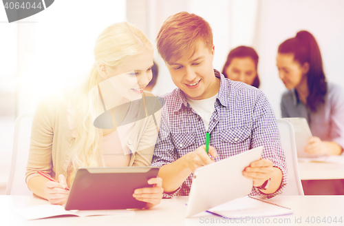 Image of two smiling students with tablet pc and notebooks