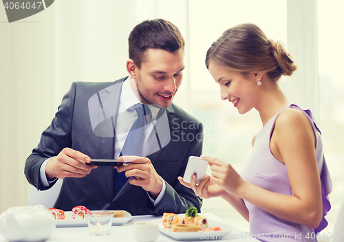 Image of smiling couple with sushi and smartphones