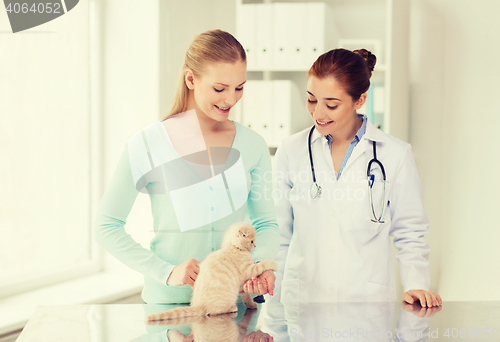 Image of happy woman with cat and doctor at vet clinic