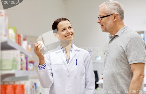 Image of pharmacist showing drug to senior man at pharmacy