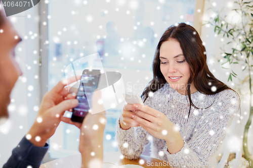 Image of happy couple with smartphones at cafe