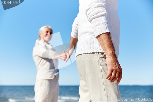 Image of close up of senior couple holding hands on beach