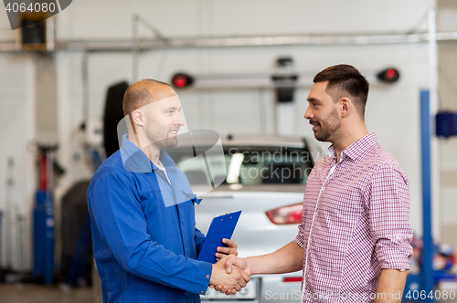 Image of auto mechanic and man shaking hands at car shop