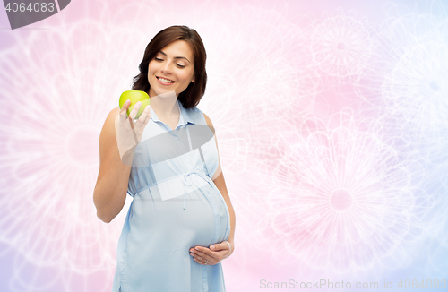 Image of happy pregnant woman looking at green apple