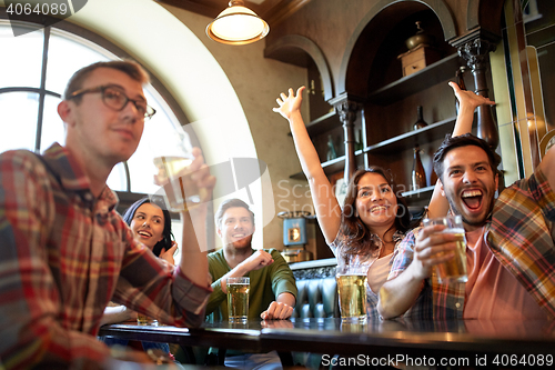 Image of friends with beer watching football at bar or pub