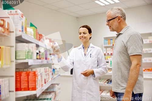 Image of pharmacist showing drug to senior man at pharmacy