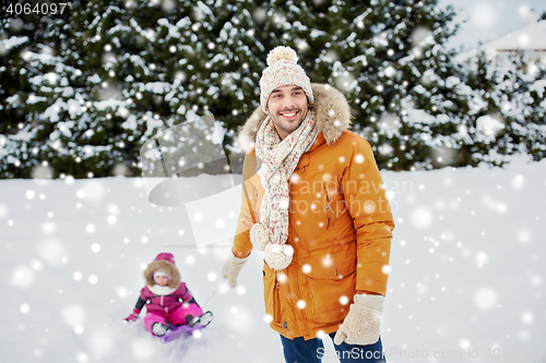 Image of happy man carrying little kid on sled in winter