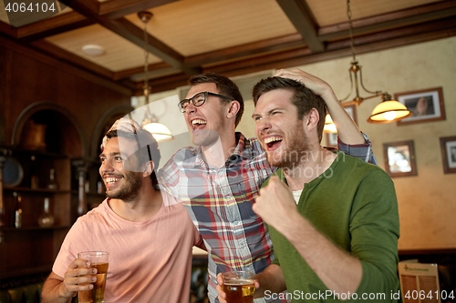 Image of friends with beer watching sport at bar or pub
