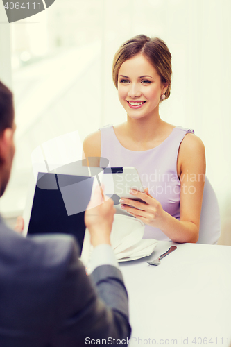 Image of couple with menus on tablet pc at restaurant