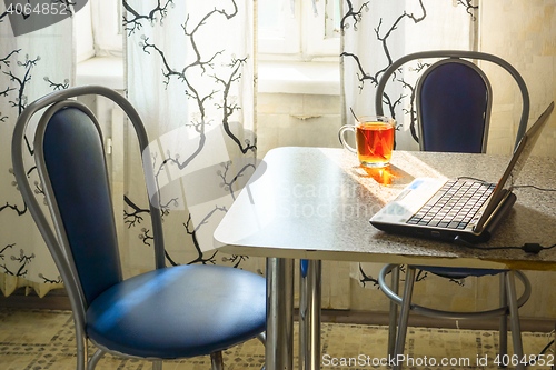 Image of Laptop and cup of tea on table