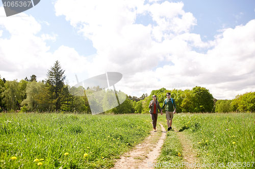 Image of happy couple with backpacks hiking outdoors