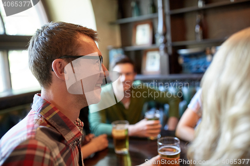 Image of happy man drinking beer with friends at bar or pub