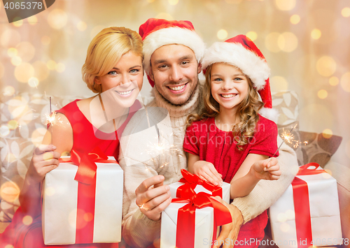 Image of smiling family holding gift boxes and sparkles