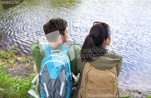 Image of couple with backpacks sitting on river bank