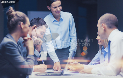 Image of smiling female boss talking to business team