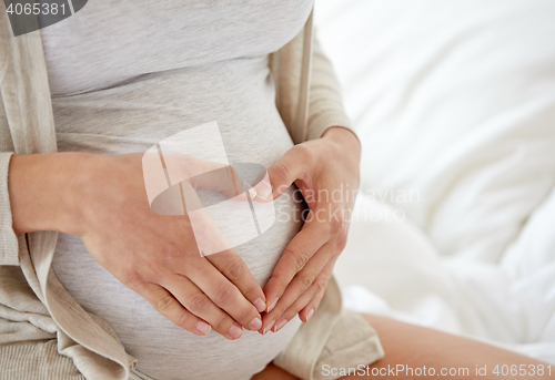 Image of close up of pregnant woman making heart gesture