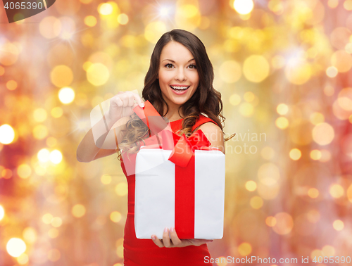 Image of smiling woman in red dress with christmas gift