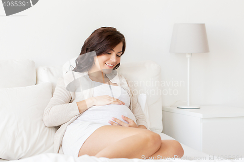 Image of happy pregnant woman lying on bed at home