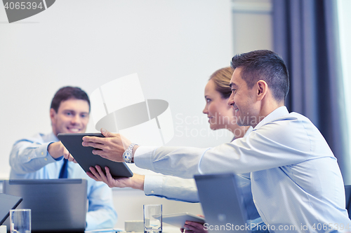 Image of smiling business people with tablet pc in office