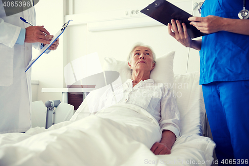 Image of doctor and nurse visiting senior woman at hospital