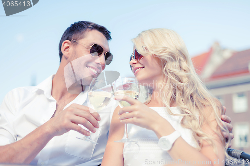 Image of smiling couple in sunglasses drinking wine in cafe