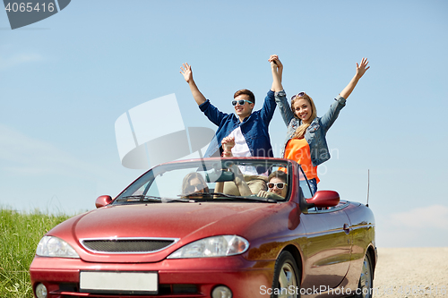 Image of happy friends driving in cabriolet car at country