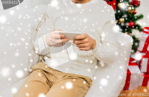 Image of smiling man with smartphone at home for christmas