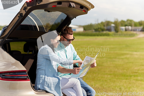 Image of happy man and woman with road map at hatchback car