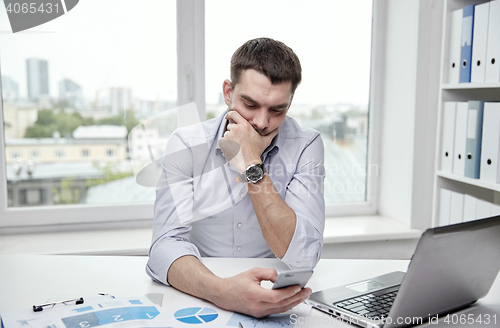 Image of businessman with smartphone and laptop at office