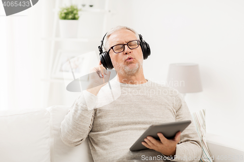 Image of senior man with tablet pc and headphones at home